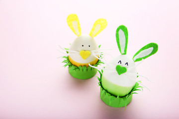 Eggs with funny rabbit faces on pink background