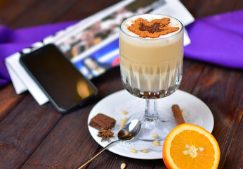 Morning cup of coffee. Warm cappuccino and morning news on a wooden textured table.