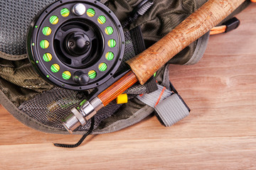 fly fishing rod with a coil and flies lie on old, wooden boards