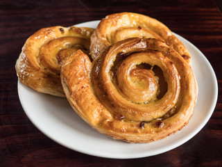 French raisin pastries on a white plate and wooden table