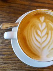 Cappuchino coffee in white porcellan cup and saucer with spoon and cinnamon close up