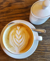Cappuchino coffee in white porcellan cup and saucer with spoon and cinnamon close up