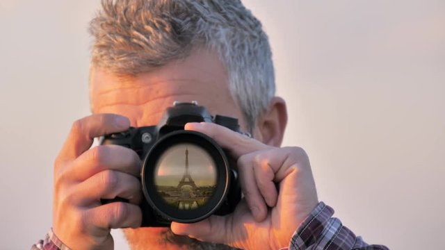 eiffel tower reflected on camera lens,man takes picture photographing paris landmark