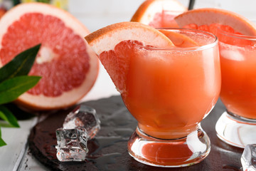 Grapefruit juice and ripe grapefruits on a wooden background