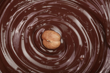 Melted chocolate swirl with hazelnut as a background closeup