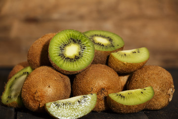 Kiwi fresh whole and halves on a black wooden table. Kiwi fruit is useful.
