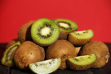 Kiwi fresh whole and halves on a black wooden table. Kiwi fruit is useful.