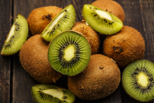 Kiwi fresh whole and halves on a black wooden table. Kiwi fruit is useful.