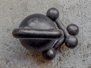 Old rusty black kettlebell and two small dumbbells on noncrete floor background