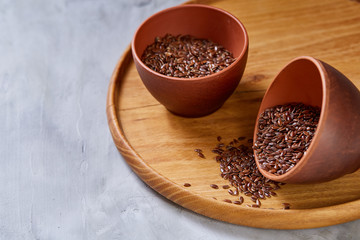 Flax seeds in bowl and flaxseed oil in glass bottle on light textured background, top view, close-up, selective focus