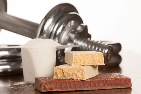 Protein bar on a teble with dumbbell in the background