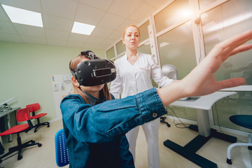 Ophthalmology doctor checks the girl's vision with the help of virtual reality goggles.