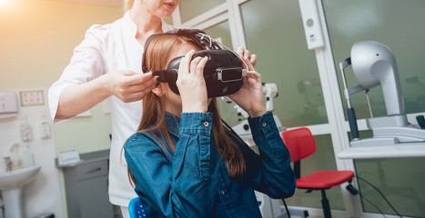 Ophthalmology doctor checks the girl's vision with the help of virtual reality goggles.