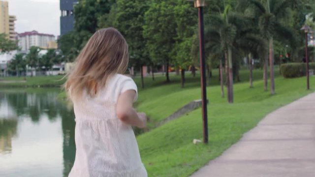 Girl in white dress running through the park. Slow motion