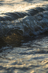 pebble stones on the sea beach, the rolling waves of the sea with foam
