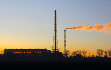 Obraz premium Industrial chemical plant in the evening at sunset pollutes the environment with harmful chemical emissions
