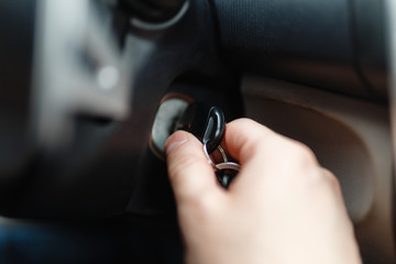 The driver of the man gets a car with a key. The hand inserts the key into the ignition and starts the car. Hand put the car key to the keyhole starting the car.