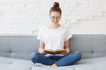 Young smiling happy woman reading on the couch