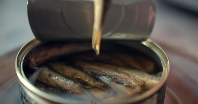 Using fork takes a smoked sardines from a tin can