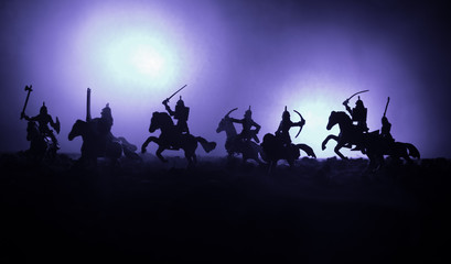 Fototapeta premium Medieval battle scene with cavalry and infantry. Silhouettes of figures as separate objects, fight between warriors on dark toned foggy background. Night scene.