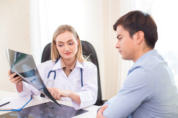 Fototapeta premium Attractive female doctor showing x-ray films to patient at clinic. Medical and Health care concept.