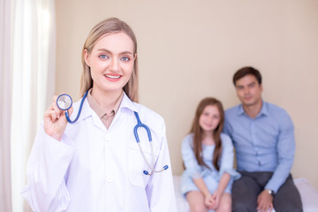 Attractive female doctor looking to camera in front of patient at clinic. Medical and Health care concept.