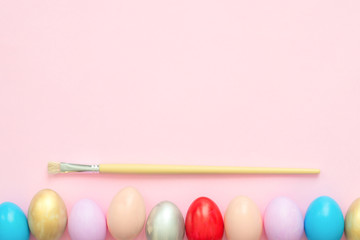 Flat lay top view colorful easter egg painted in pastel colors composition with paint brush on pink pastel color background. Easter day background top view with copy space.