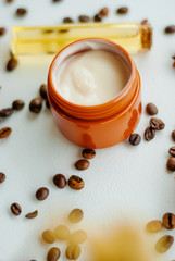 Jar of caffeine cream and coffee beans on white background, top view