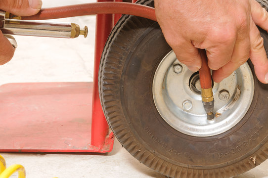 Mechanic putting air in the small tire of a hand cart