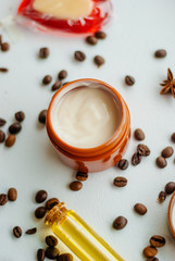 Jar of caffeine cream and coffee beans on white background, top view
