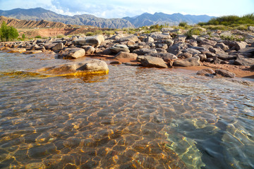 The shore of a mountain lake with clear clear water.