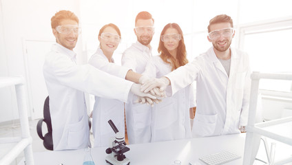 successful team of young scientists with hands clasped together.