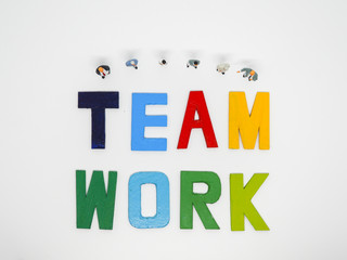 Miniature bussinessman with TEAMWORK word letters on white background, business concept.