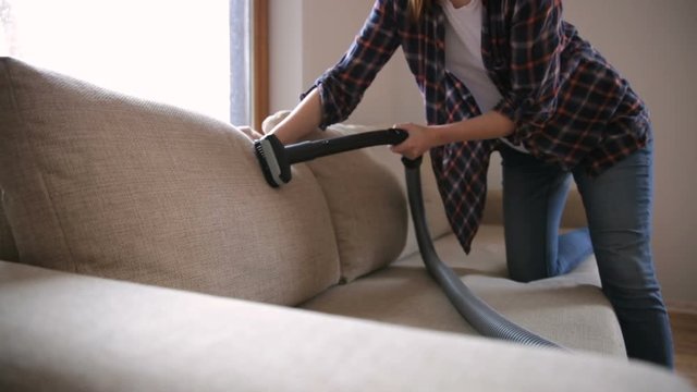 Woman cleaning the sofa, couch with vacuum cleaner