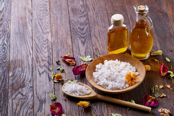 SPA concept: composition of spa treatment with natural sea salt, aromatic oil and flowers on wooden background