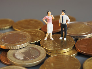 Miniature couple stand on Euro coins. Family future money plan concept.