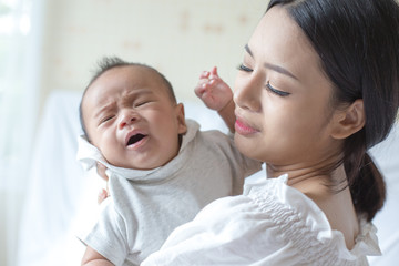 Mothers holding baby boy in hand. Baby crying in mother hand.