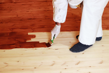 Decorator paints the floor with brown paint
