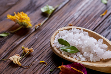 SPA concept: composition of spa treatment with natural sea salt, aromatic oil and flowers on wooden background