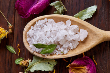 SPA concept: composition of spa treatment with natural sea salt, aromatic oil and flowers on wooden background