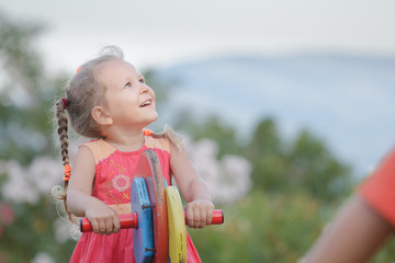 Recreational activity of little kid girl swinging on wooden playground equipment summer outdoors