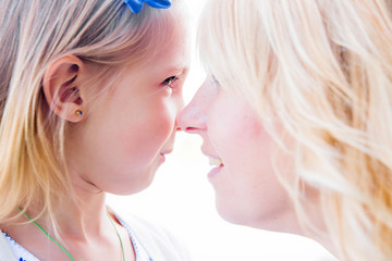 Mother and daughter hugged each other with their noses, look in 