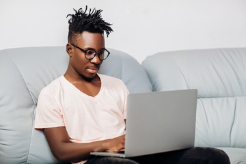 African American man sitting with laptop on sofa