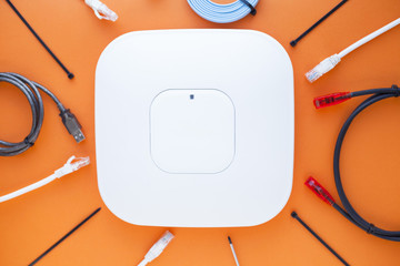 Corporate network concept. Set of ethernet switches, access points, cables, connectors, laptops on the orange background. Top view. Space for a text. Close up.