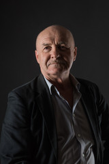 Obraz premium Elderly positive male businessman on a dark background
