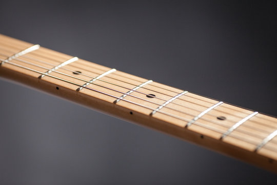 Close up detail of the neck of electric guitar . Musical instrument. Black background