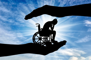 Silhouette of sad disabled woman in wheelchair in hands of help