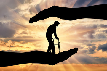 Silhouette of a disabled man with a walker for the disabled in the hands of help