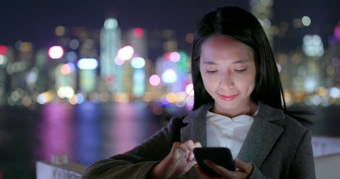 Businesswoman look at cellphone in city at night