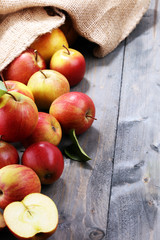 Ripe red apples with leaves on wooden background.